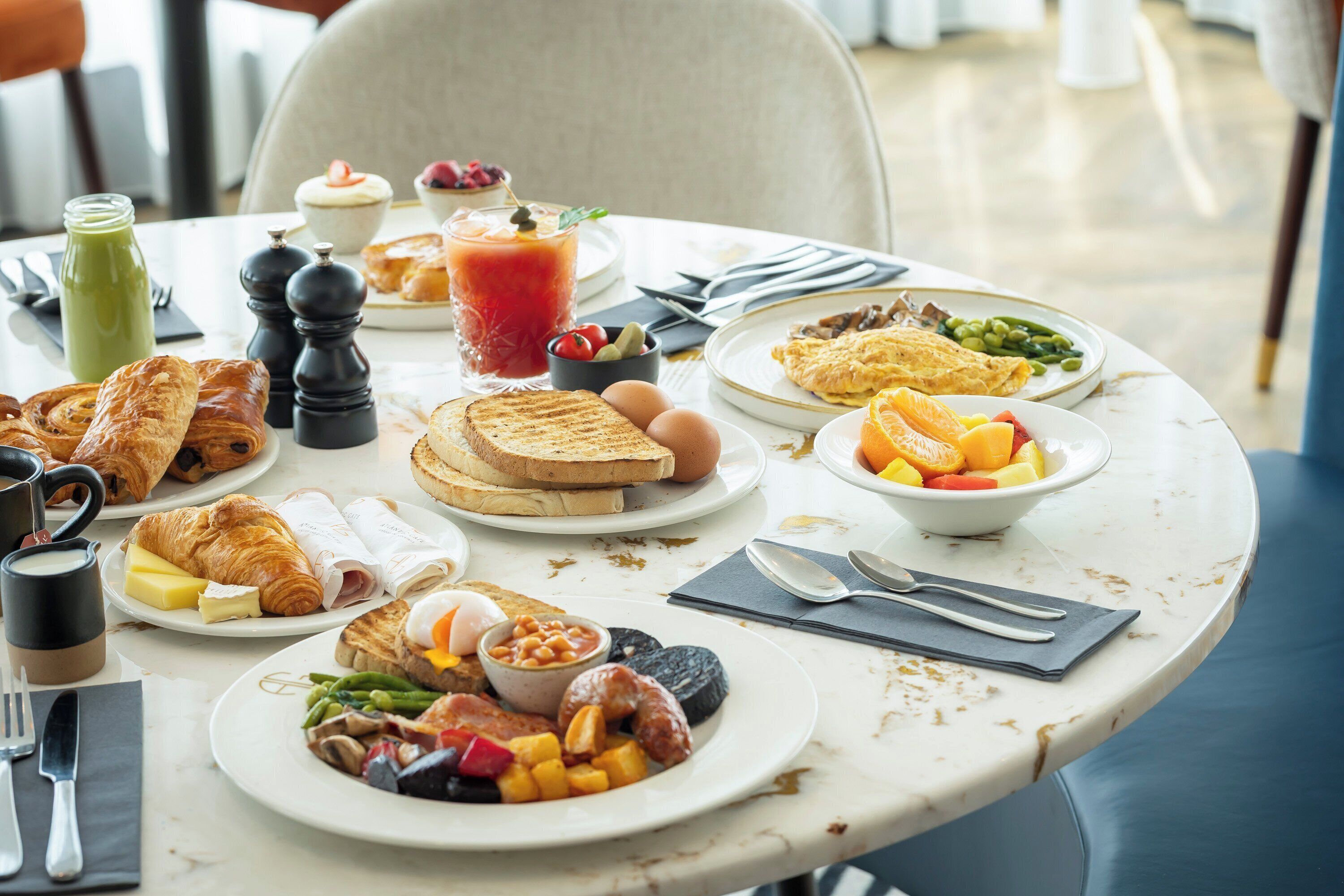 Une table de petit-déjeuner avec divers aliments, notamment des toasts, des œufs et des fruits.