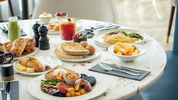 Een ontbijttafel met diverse soorten eten, zoals toast, eieren en fruit.