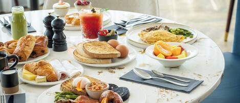 Une table de petit-déjeuner avec divers aliments, notamment des toasts, des œufs et des fruits.