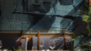 Un comedor con una mesa preparada para dos, un banco estampado y vistas a un puente a través de una ventana.