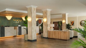 Een receptie met een marmeren balie, een houten receptie en een moderne kroonluchter.
