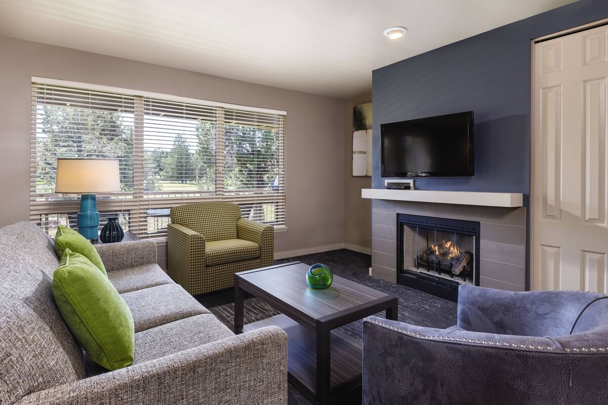 A modern living room with a fireplace, a flat-screen TV, and comfortable seating.