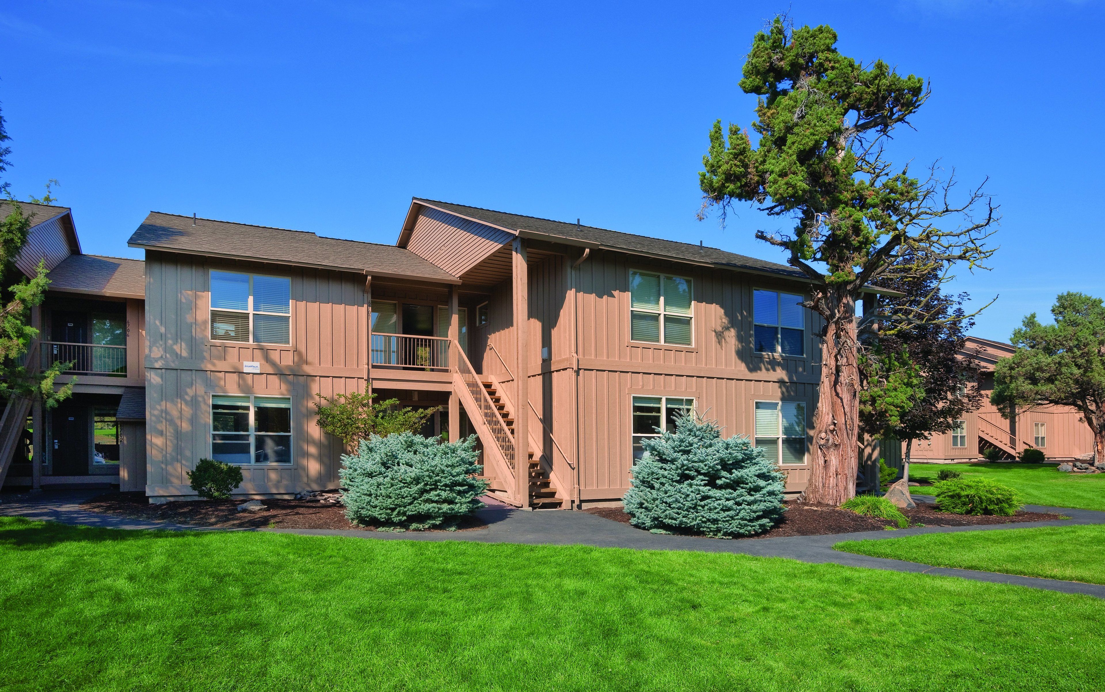 A two-story building with a brown exterior, multiple windows, and a staircase leading to a balcony.