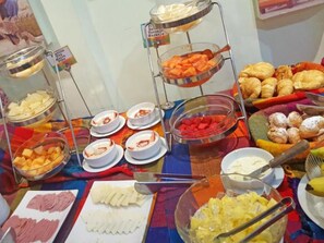 A buffet with various food items including meats, cheeses, and pastries.
