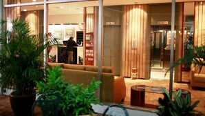 A modern hotel lobby with a reception desk, seating area, and a glass elevator. - Hotel Continental (Guayaquil)