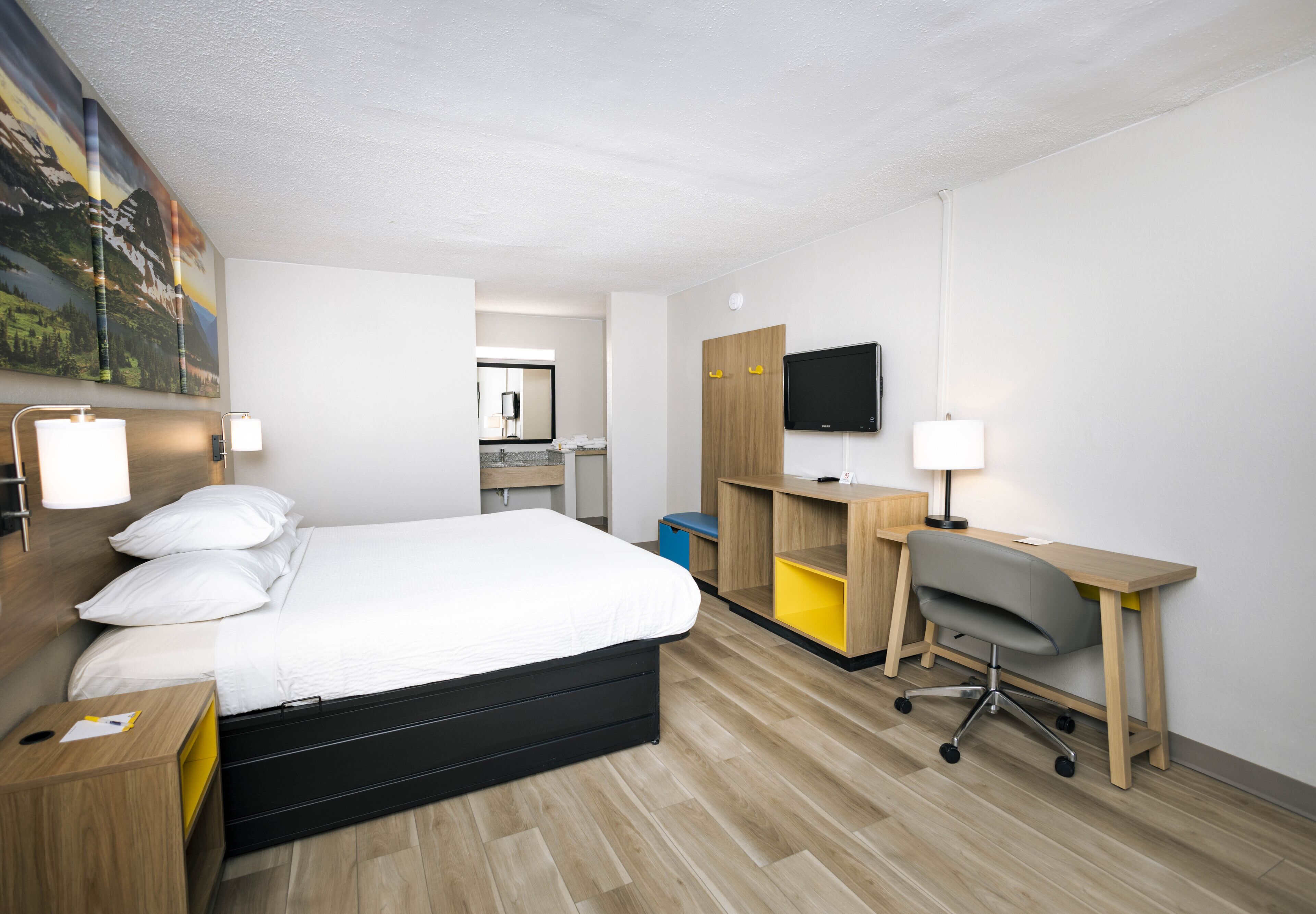 Una habitación de hotel moderna con cama, escritorio, silla y televisor.