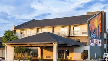 Welcome to Charleston, where a vibrant cityscape mural adorns the exterior of this two-story motel, offering a charming entrance to your stay.