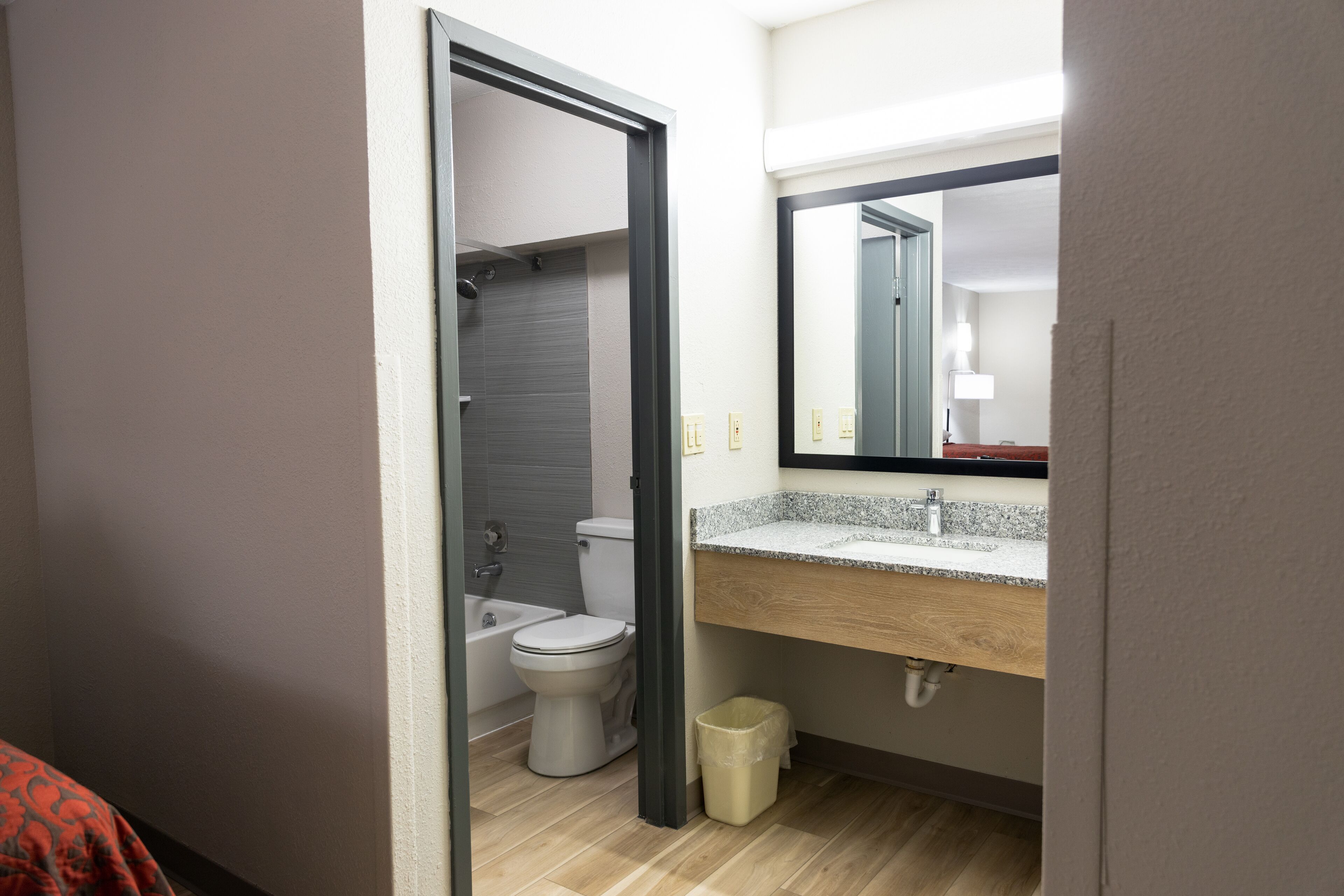 A bathroom with a toilet, sink, mirror, and shower.