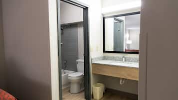 A bathroom with a toilet, sink, mirror, and shower.