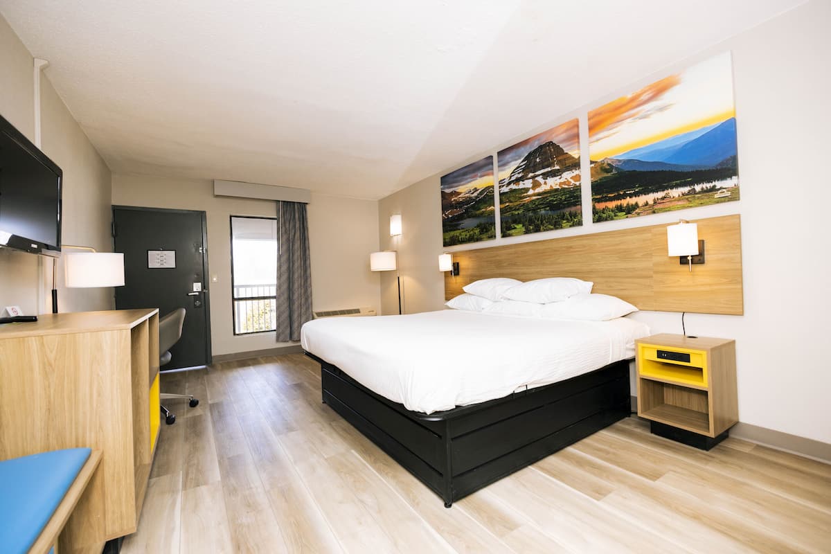 Ein modernes Hotelzimmer mit Bett, Nachttischen, einem Schreibtisch und Bildern an der Wand.