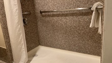 A shower area with a white shower curtain, a metal grab bar, and a towel rack.