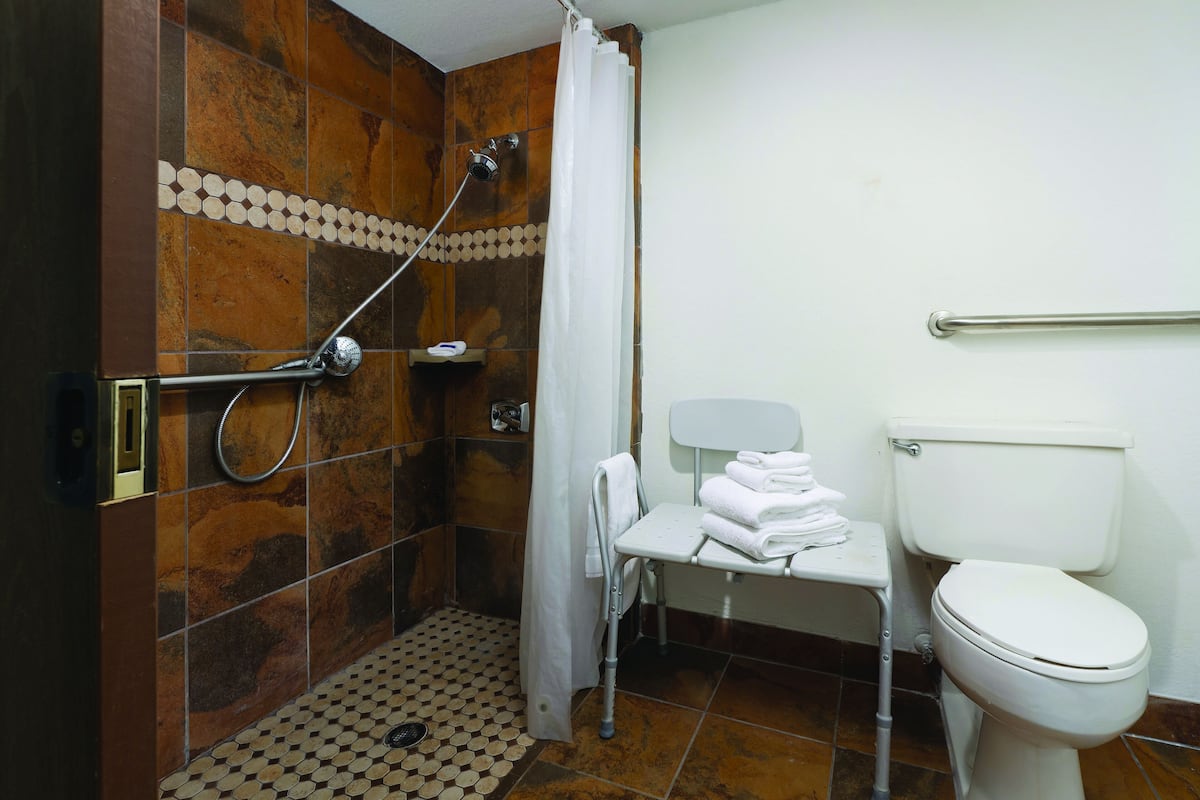 Ein Badezimmer mit Dusche, Toilette und einem kleinen Tisch mit Handtüchern.
