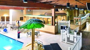 An indoor pool area with a reception desk, lounge chairs, and a palm tree decoration. - Western Heritage Hotel and Conference Center, an Ascend Collection Hotel (Casper)