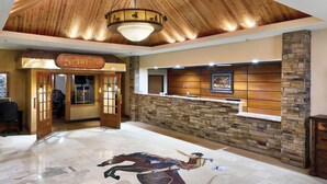 A lobby with a reception desk, a stone wall, and a large dragon mural on the floor. - Western Heritage Hotel and Conference Center, an Ascend Collection Hotel (Casper)