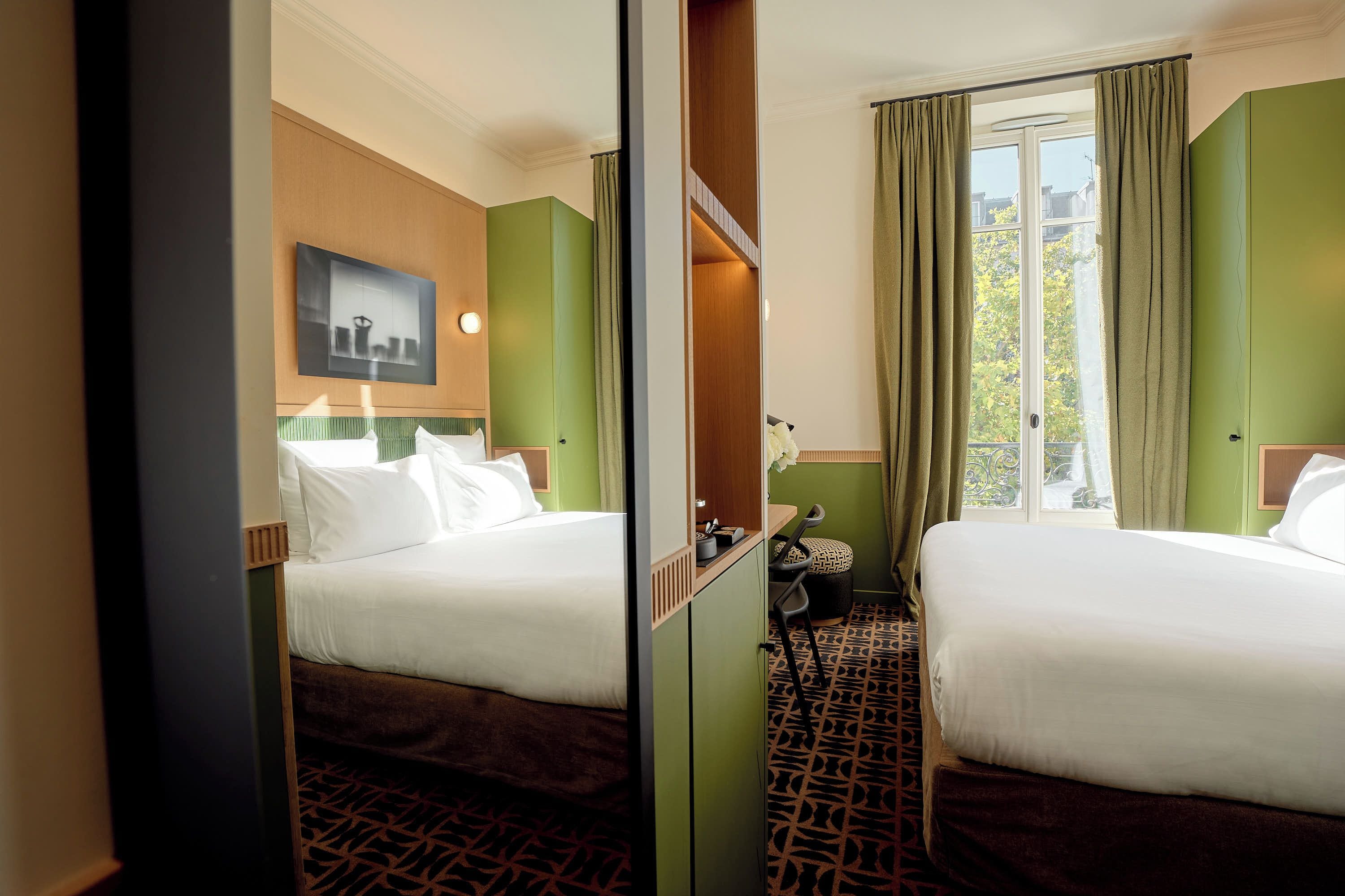 Habitación de hotel con dos camas, un espejo, una ventana con cortinas y una pared verde.
