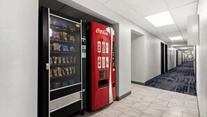 Un pasillo con máquinas expendedoras, incluyendo una máquina de Coca-Cola, y piso alfombrado.