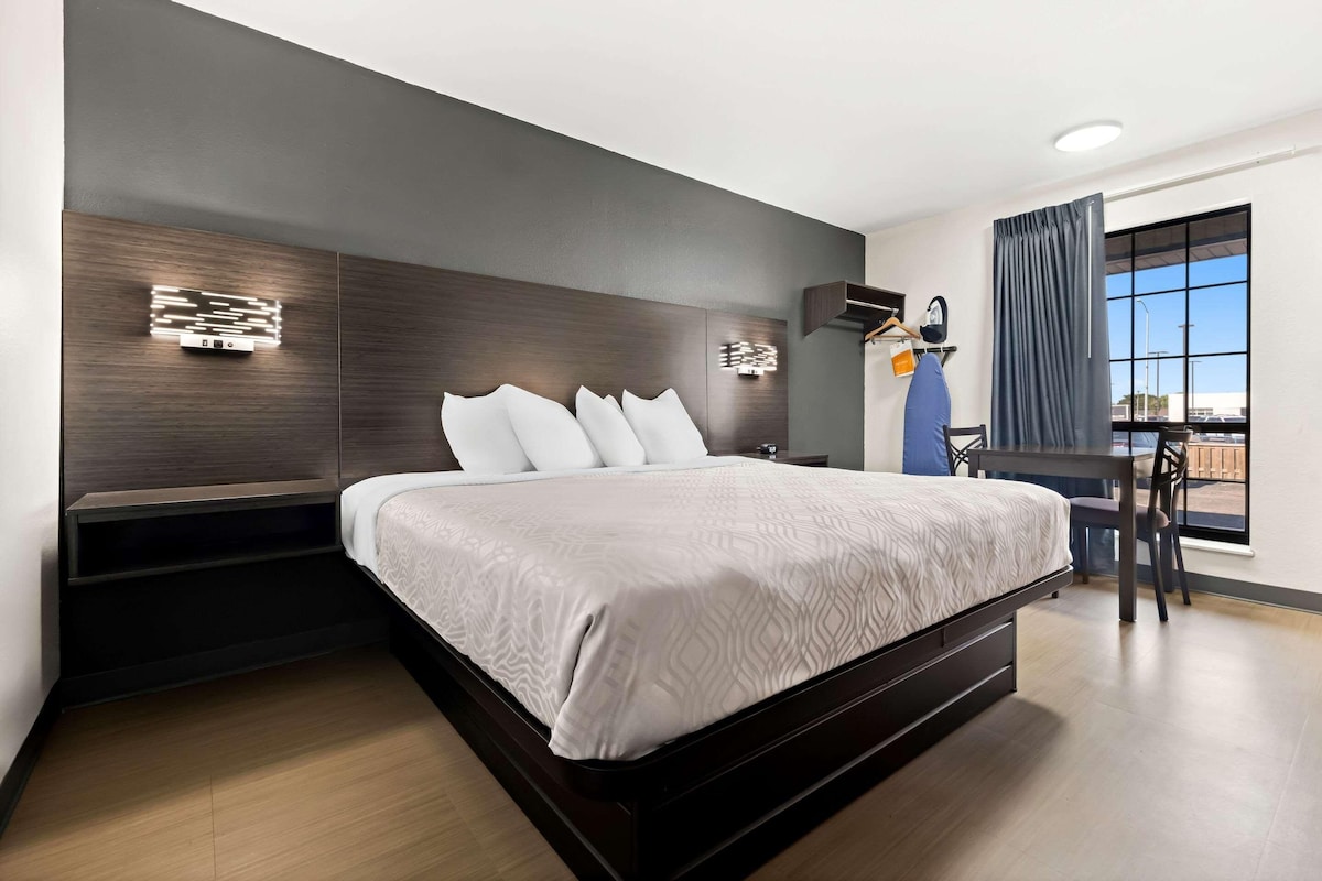 Habitación de hotel moderna con una cama grande, un escritorio y vistas al exterior.