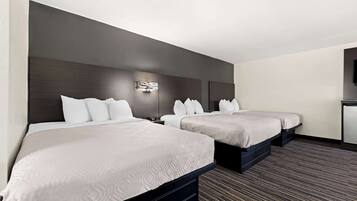 A hotel room with two beds, a dark headboard, a wall-mounted light, and a carpeted floor.