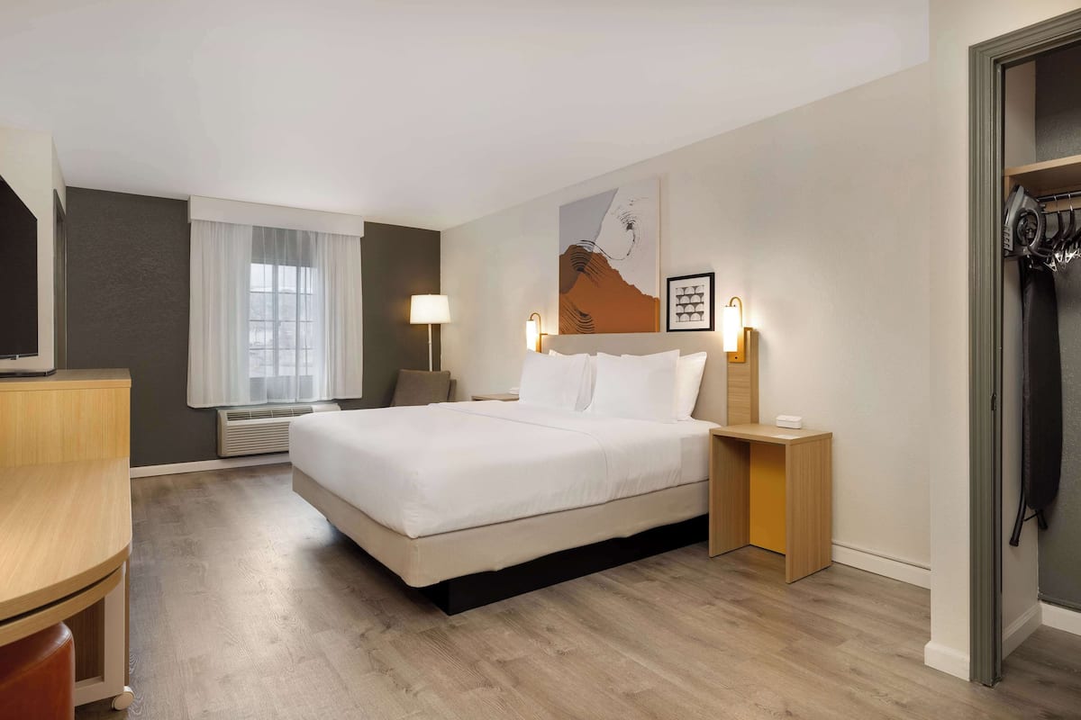 A hotel room with a large bed, bedside tables, a desk, and a wardrobe.