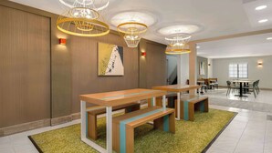 A modern hotel lobby with wooden benches, a green carpet, and pendant lighting. - Spark by Hilton Rock Springs (Rock Springs)