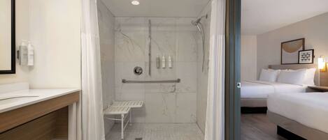 Un bagno moderno con doccia, una panca e un mobile lavabo con articoli da toilette.