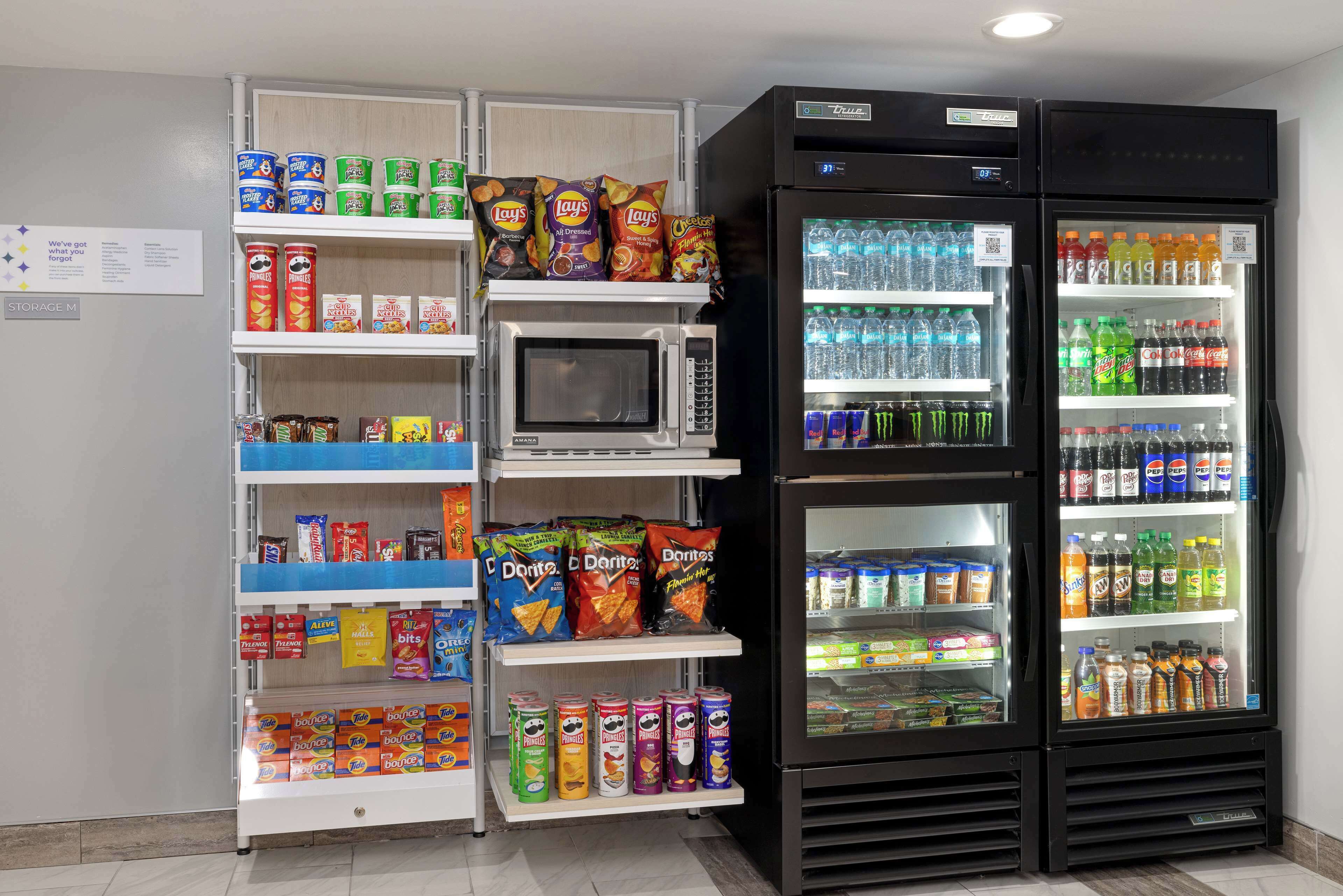 Un distributeur automatique de collations et de boissons, un four à micro-ondes et un réfrigérateur rempli de boissons.