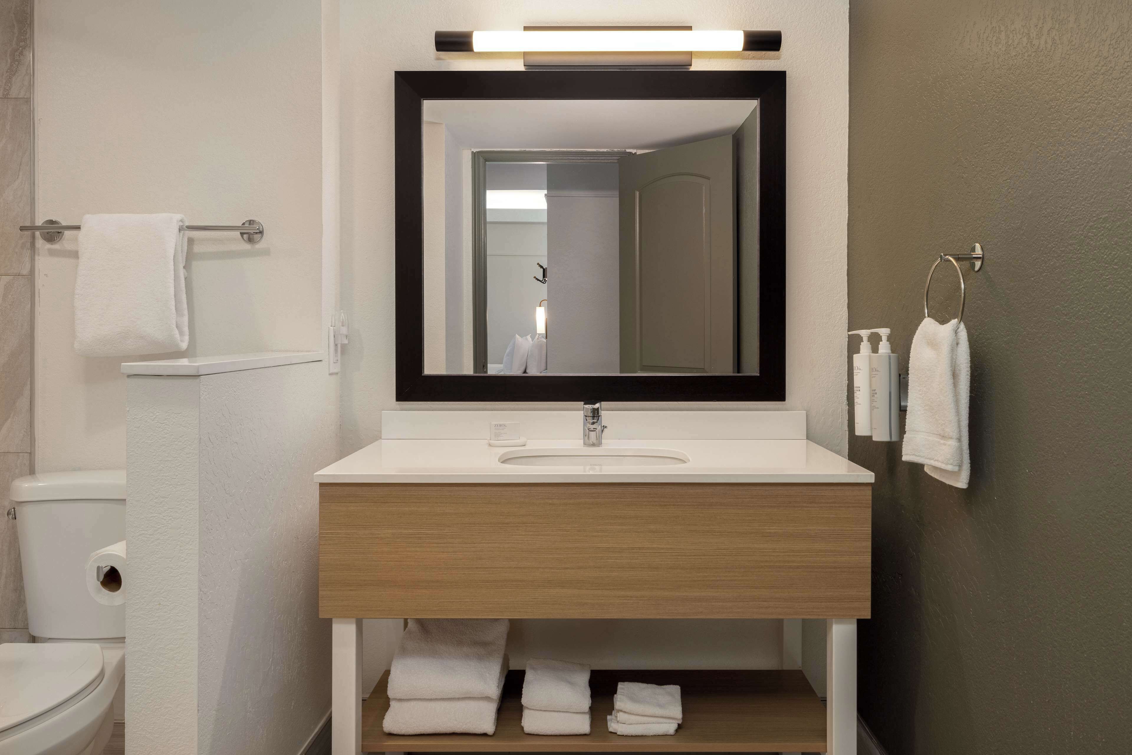 Un bagno moderno con lavandino, specchio e portasciugamani bianchi.