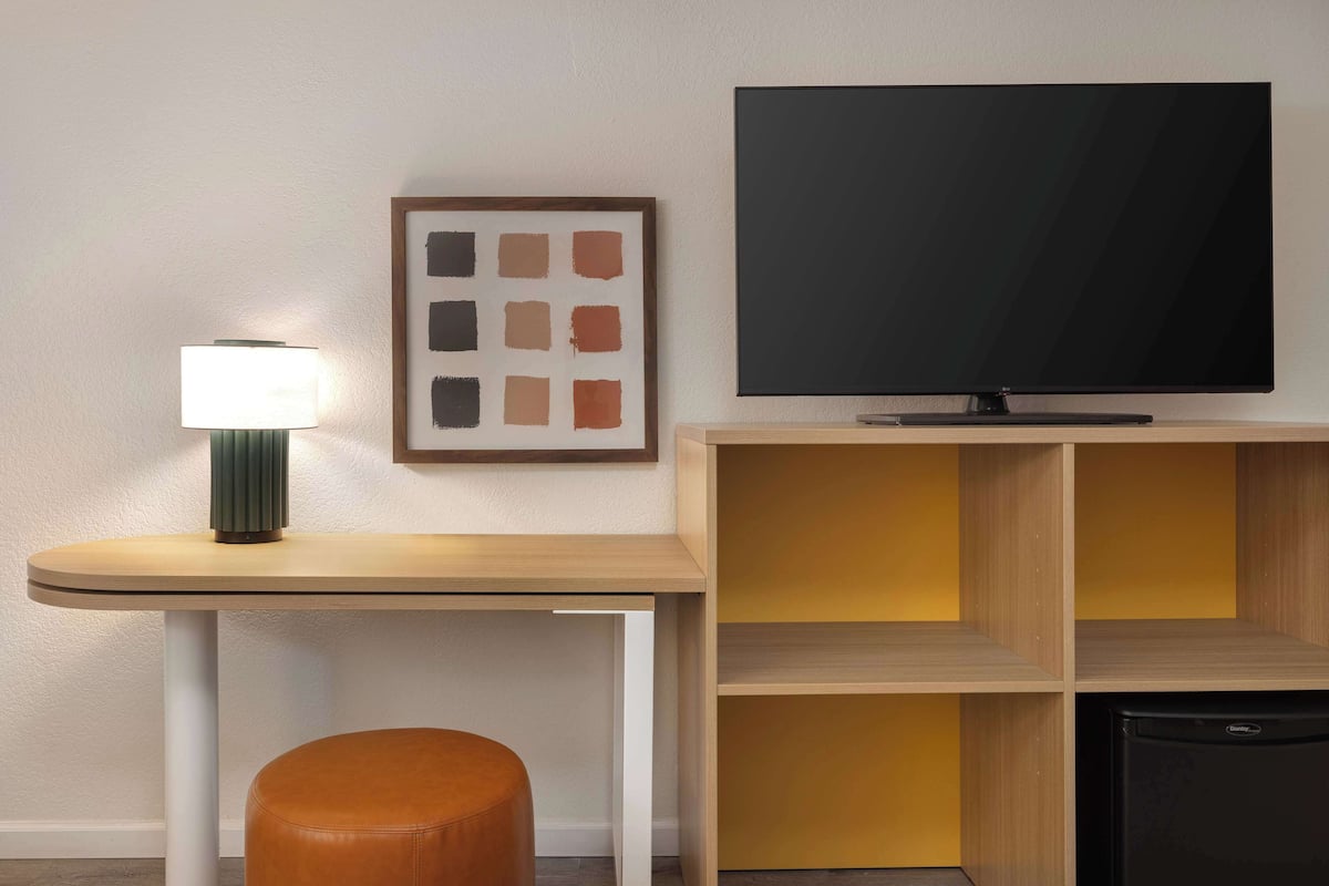 A modern room with a TV, a lamp, a framed picture, and a wooden cabinet.