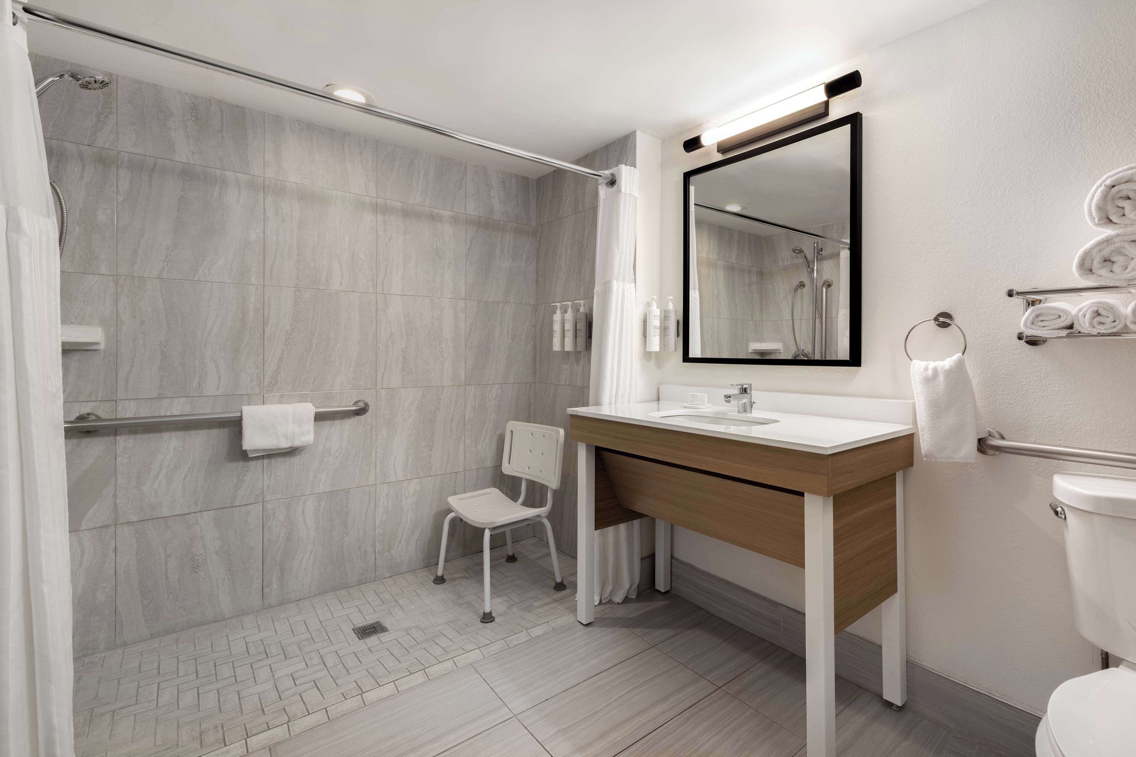 Un baño moderno con ducha, lavamanos, espejo e inodoro.
