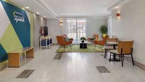 A modern lobby with a seating area, a reception desk, and a large window with curtains. - Spark by Hilton Rock Springs (Rock Springs)