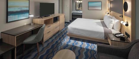 Habitación de hotel con cama, escritorio, silla y televisión.