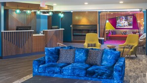 A modern lobby with a blue sofa, yellow chairs, a reception desk, and a colorful wall mural. - Accent Inns Vancouver Airport (Richmond)