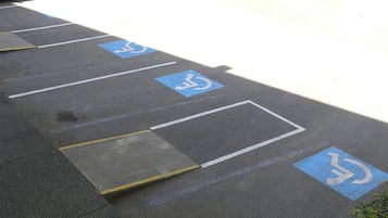 Un estacionamiento con espacios reservados para discapacitados señalizados con pintura azul y símbolos de sillas de ruedas.