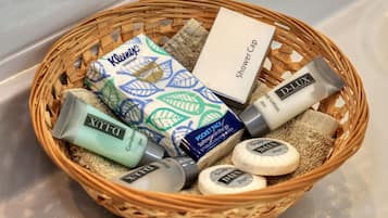 A wicker basket containing toiletries including a shower cap, body lotion, and soap.