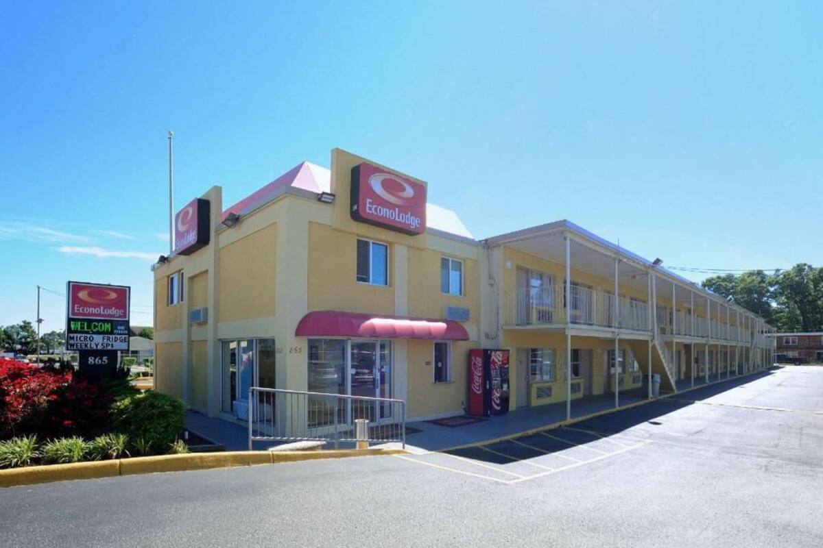 A motel with a red awning, a Coca-Cola vending machine, and a sign indicating a micro-fridge and weekly specials.