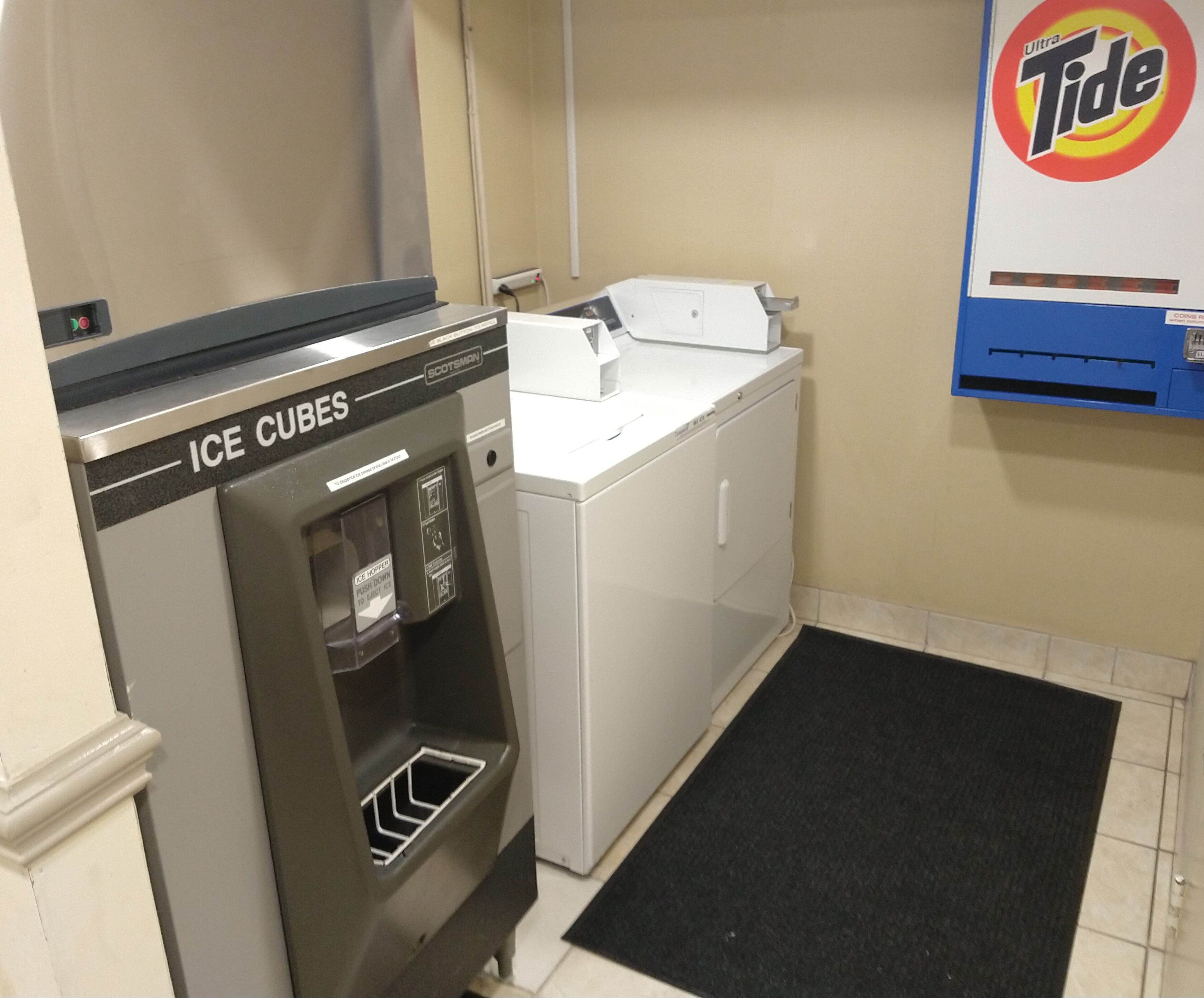 A laundry area with an ice cube dispenser, a washing machine, and a Tide detergent dispenser.