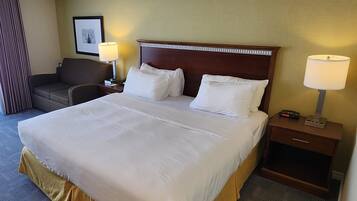 Une chambre d’hôtel avec un grand lit, deux tables de chevet, une chaise et une lampe.