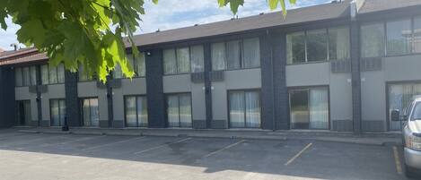 Un motel à plusieurs étages, doté d’un parking, de grandes fenêtres et d’un véhicule stationné sur le parking.