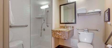 Une salle de bain moderne avec une douche à parois de verre, des toilettes blanches, un lavabo en granit et un miroir au-dessus du lavabo.