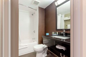A modern bathroom with a bathtub, toilet, and vanity with a mirror.