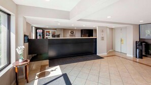 A hotel reception area with a modern design, a reception desk, a coffee machine, and a refrigerator.