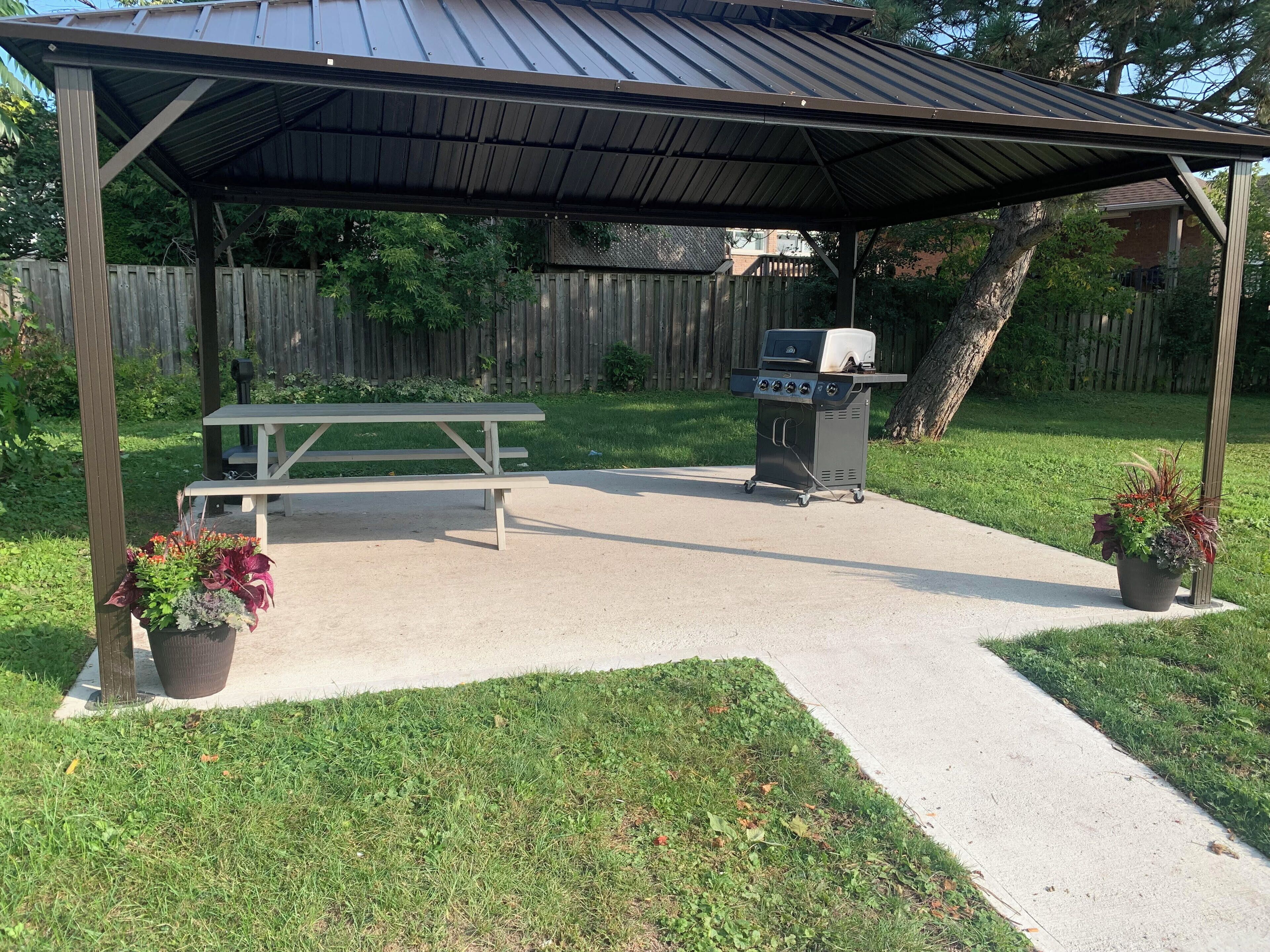 An outdoor patio with a picnic table and a barbecue grill.