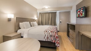 A hotel room with a bed, bedside tables, a desk, and a TV on the wall. - Red Roof Inn Durham - Triangle Park (Durham)
