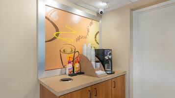 A reception desk with a coffee machine, a trash bin, and a wall with a motivational quote.