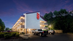 A Red Roof Inn with a modern design, featuring a prominent red sign, a parking lot with several vehicles, and a well-lit entrance. - Red Roof Inn Durham - Triangle Park (Durham)