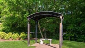 A gazebo with a bench, surrounded by grass and trees. - Red Roof Inn Durham - Triangle Park (Durham)