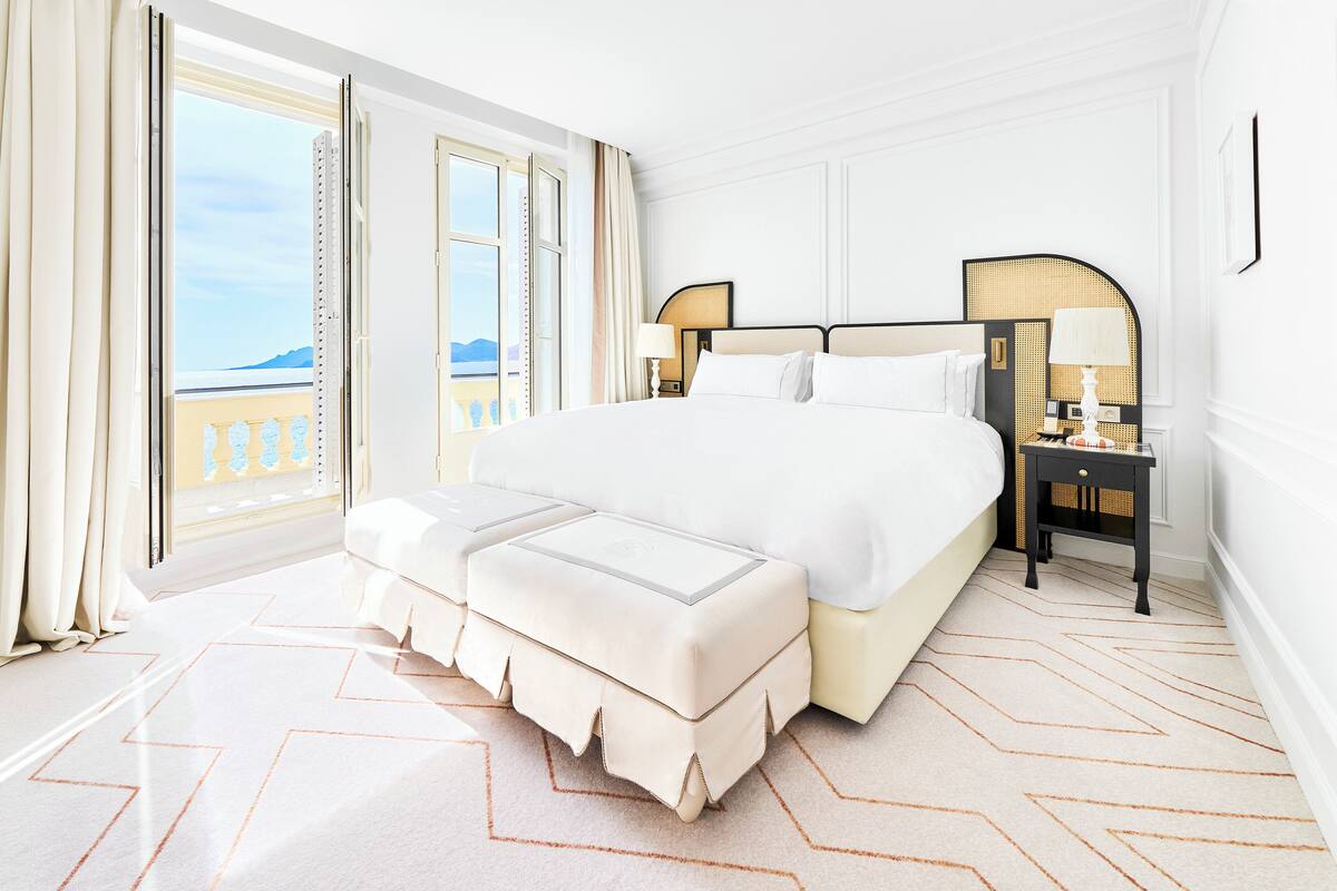 A spacious bedroom with a large bed, a bedside table, and a view of the outdoors.