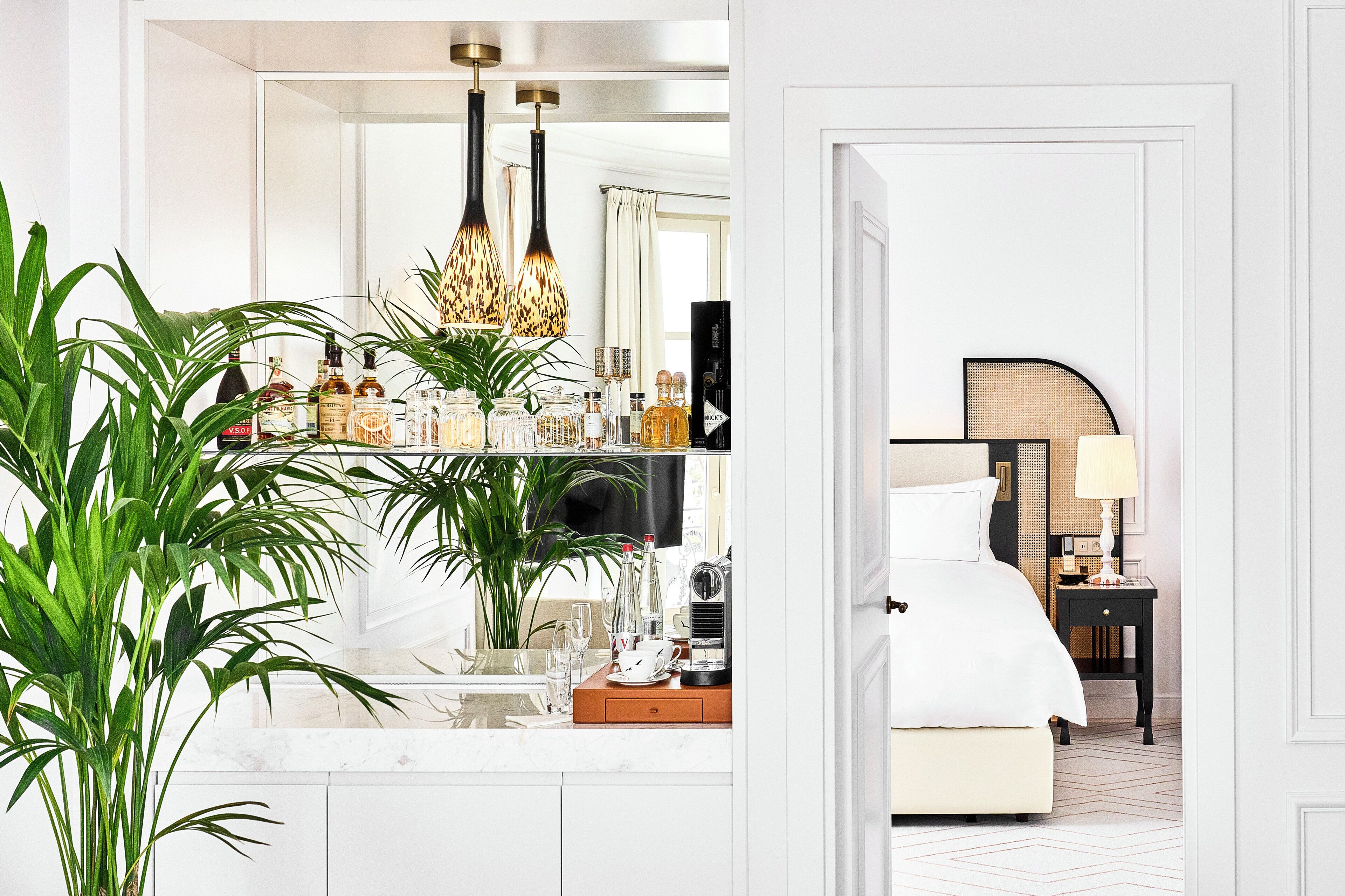 A modern hotel room with a large mirror, a bedside table with a lamp, and a bed with a headboard.