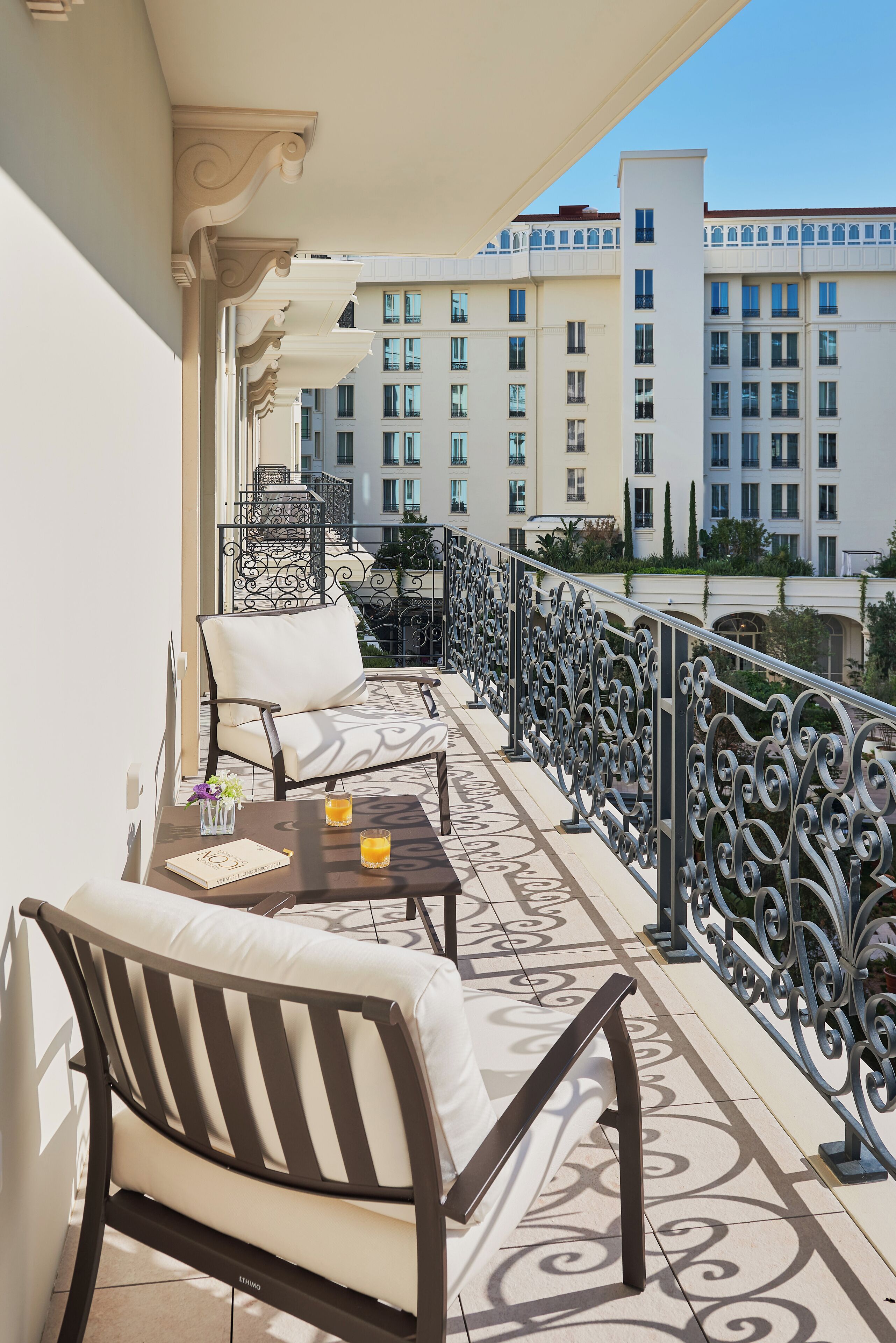 A balcony with two sofas and a table, a decorative railing, and a view of high-rise buildings.