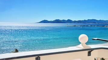 A balcony with a clear view of a turquoise sea and distant mountains.